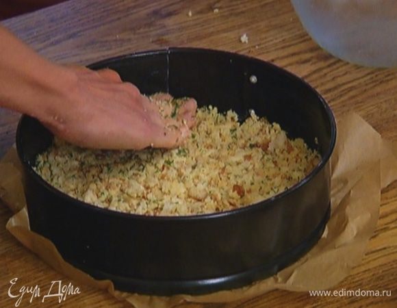 Разъемную форму выстелить бумагой для выпечки, смазать ее оставшимся сливочным маслом, выложить крошку, разровнять и слегка утрамбовать. Корж должен получиться толщиной примерно в 1 см. Поставить форму в морозильник.