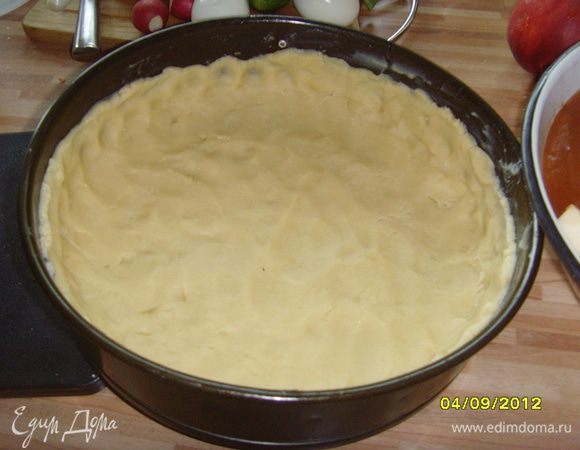 Замесить тесто из муки с разрыхлителем, холодного масла, сахара, яйца, соли с добавлением 1–2 ст. л. ледяной воды, распределить по круглой разъемной форме (у меня 26 см в диаметре), сформировать высокий бордюр. Форму предварительно выложить пекарской бумагой или смазать сливочным маслом. Поставить в холодильник.