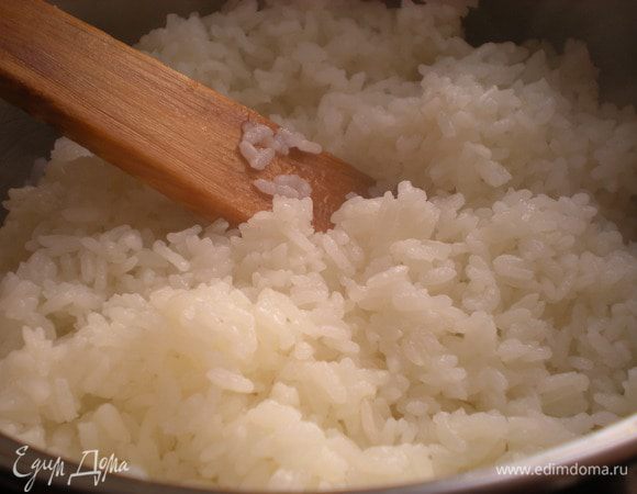 Снять кастрюлю с огня и дать рису постоять 20 минут с закрытой крышкой. Затем легкими движениями распушить рис деревянной лопаткой, пока он горячий.