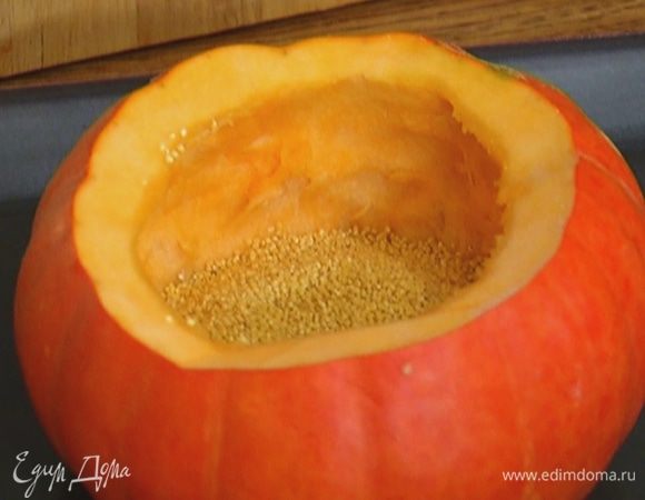 Поместить тыкву на противень, всыпать внутрь пшено, так чтобы оно наполовину заполнило тыкву.