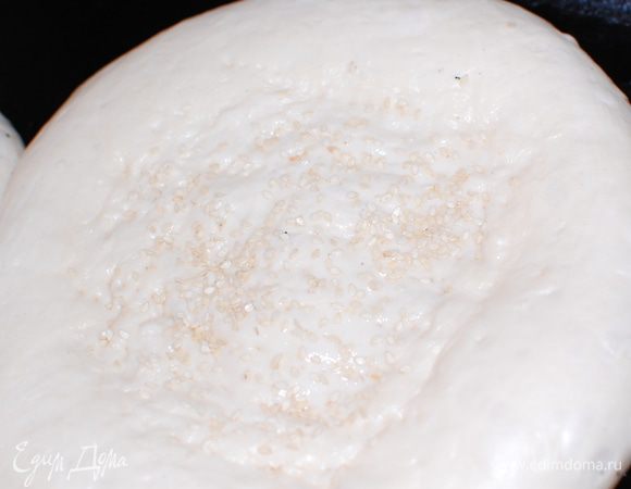 Дайте лепешкам подойти, смажьте их теплой водой и посыпьте кунжутом.