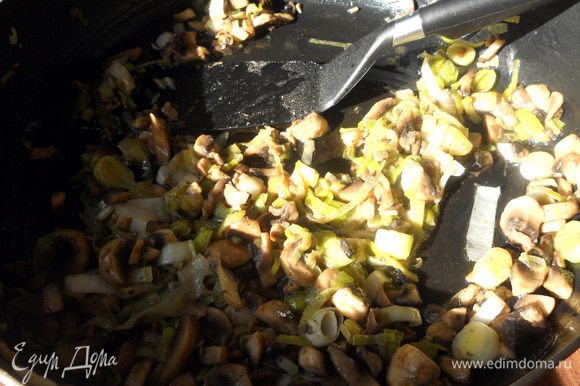 В сковороде разогреть немного оливкового/растительного масла, обжарить лук-порей (нежную часть), минут 10, не давая потемнеть. Присоединить тонко порезанные шампиньоны и готовить еще 10 минут, или до желаемого состояния грибов.
