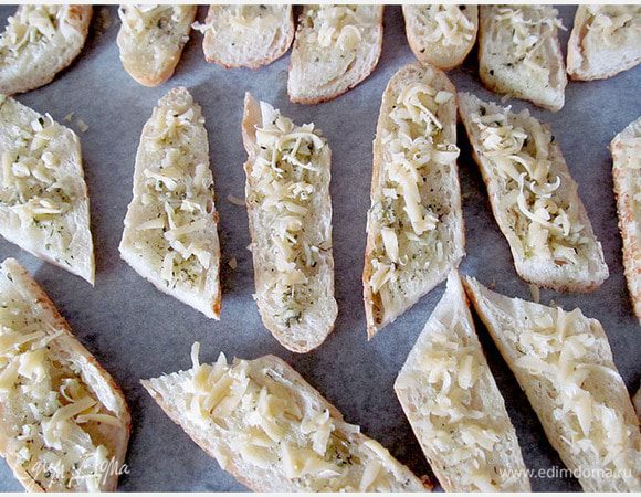 Хлеб смазываем заправкой, можно прямо макать хлеб в заправку. Выкладываем его на противень с пергаментом. Посыпаем сыром, можно обойтись и без него. Выпекаем в духовке при 160 гр. до золотистого цвета.