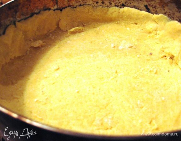 Духовку разогреваем до 180 градусов. Тесто делим на две части. Раскатываем первый пласт и выкладываем в форму, выстланную пергаментной бумагой. Делаем бортики. 