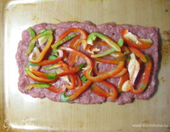 Сборка мясного хлеба.
Духовку разогреть до 200оС.
Противень или форму для запекания (у меня большой стеклянный противень) смазать оливковым маслом.
Выложить 1/4 часть фарша на противень тонким слоем около 5 мм в форме вытянутого прямоугольника.
Сверху выложить половину нарезанного сладкого перца, края по всему периметру оставить без начинки.