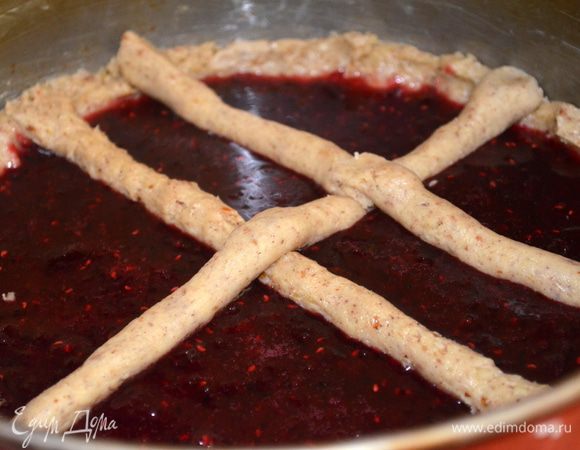 второй кусок делим на маленькие кусочки и скатываем их в тонкие колбаски. Это проще делать чуть смоченными руками, так как тесто немного липнет к рукам и красиво раскладываем в виде решетки на пирог