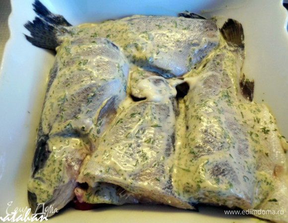 Лимон помыть, обсушить и разделить пополам.Отрезать 2 кружка лимона, которые разделить пополам, а из остальной части половинки выжать лимонный сок.Смешать майонез, горчицу, лимонный сок, соль и зелень. Форель почистить, вымыть и обсушить бумажным полотенцем. Рыбу разрезать поперёк пополам и обмазать со всех сторон майонезно-горчично-лимонной смесью. Лук почистить, помыть и обсушить. Нарезать его кольцами, которыми выложить дно формы. Поверх лука положить рыбу, которую слегка посолить, поперчить и посыпать сушёным чесноком.