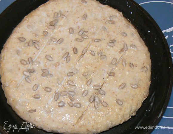 Из теста сделать  лепешку, выложить на противень, острым ножом сделать сверху 3 параллельных надреза, смазать молоком, посыпать оставшимися  семечками, накрыть полотенцем и оставить в теплом месте ..