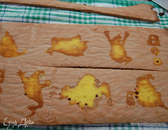 Взять за края пергамент бумаги и снять с противеня бисквит с рисунком. Переверните на подготовленную поверхность (в моем случае – кухонное полотенце) бумагой вверх и снимите её. Подравнять края острым ножом. Вот видете, что у меня получилось…. Признаться честно, визуально я расчитывала на несколько иной результат.  Контур получился не четким, шоколадное тесто в некоторых местах смешлось с оранжевым и образовались  пятна.  А еще я так торопилась с нанесением шоколадного теста, что сделала края слишком тонкими и они подгорели. Немножко огорчилась.  