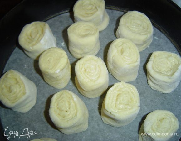 Форму застилаем пергаментной бумагой, на нее выкладываем рулетики на расстоянии 1-1,5 см друг от друга. Оставляем их на расстойку до увеличения и заполнения формы.