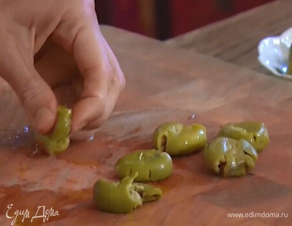 Оливки раздавить плоской стороной ножа и удалить косточки.