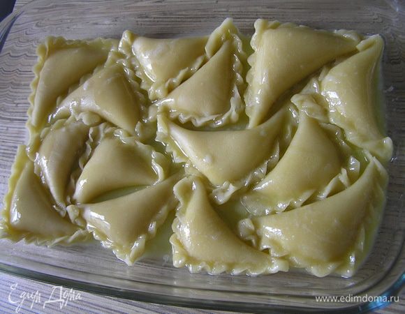 Выложить вареники в смазанную маслом форму для запекания. Сверху полить растопленным сливочным маслом,