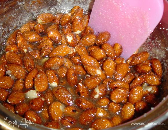 Пока крем остывает, готовим пралине. В нагретую сковороду кладем миндаль, сверху 100 г сахара,  жарим орехи, постоянно перемешиваем и доводим до такого состояния, когда сахар превратится в карамель (нельзя допустить подгорания). Затем орехи выкладываем на пергамент, смазанный маслом, даем остыть, а затем измельчаем карамель с орехами.