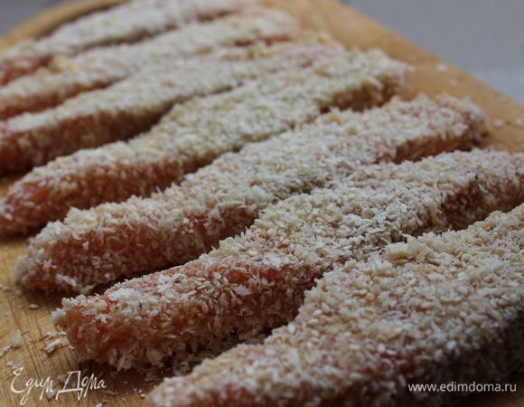 Каждый ломтик обмакнуть в муку, потом окунуть в яйцо и обвалять в хлебной крошке с кунжутом. Выложить на доску и поставить в холодильник на 30 минут. На этом этапе рыбные палочки можно заморозить для хранения. 