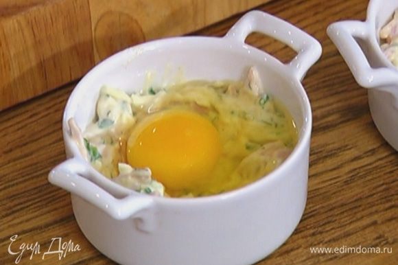 Разложить сырную массу в 4 кокотницы, сделать в середине небольшие углубления и разбить в каждое по одному яйцу, посолить и поперчить.
