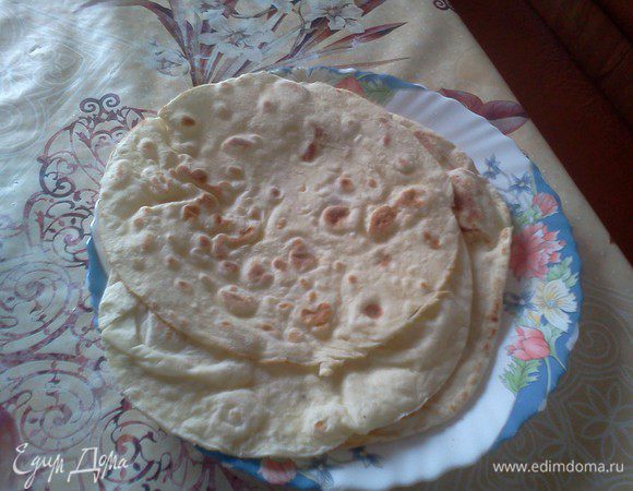 ТЕСТО.
Я делаю так . В небольшую кастрюльку выливаю воду добавляя соль ,сахар и дрожжи. Перемешал. Оставил на минут 5-10.. Чтоб дрожжи как бы растворились . Потом еще разик перемешать, чтоб все  растворилось.. далее просеиваем муку , перемешивая ложкой , чтоб не было казусов в плане прилипания теста к рукам. После просеивания муки вольем туда растительное масло (оно то и препятствует прилипанию теста самого).Далее вымешиваем его и отставляем в теплое место на часик чтоб подошло. 
РАСКАТКА.. Я делал так. Отрывал понемногу теста (чтоб в ладошку помещался шарик) и очень тонко его раскатывал (чтоб виднелся рисунок на клеенке). Далее брал тарелку круглую и поставив её как трафарет обрезал края лепешки дабы она оставалась круглой. 
ВЫПЕЧКА.
На голую хорошо разогретую толстую сковороду кладем лепешку.. как она поднимется , переворачиваем. И так до конца (единственное что меня самого не радует в этом. Так как после лепешек на сковороде остается мука, она начинает поджариваться и немного дымить... Поэтому много за раз я их не пеку).. 
В ИТОГЕ.
Получатся мягкие приятные лепешки на подобие лавашей.. Но они круглы и делались не в тандыре. А значит Тортильи. Их можно использовать для создания бурритос, кесайдильи, фахитос, и чего еще может душа пожелать.
Я их начинил рубленым куриным филе обжаренным с чесноком , прованскими травами и помидорами . И еще раз обжарил  на растительном масле.
