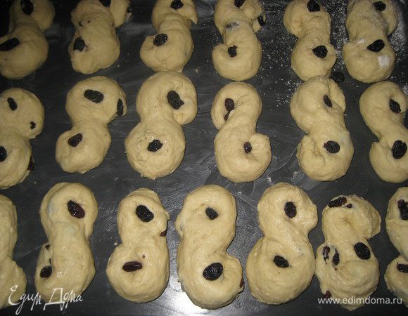 Раскатываем из теста длинные колбаски и скручиваем булочки в виде латинской буквы S. В ячейки с каждой стороны вставляем по одной изюминке. Перекладываем булочки на смазанный маслом противень и оставляем подходить 20-30 минут.





