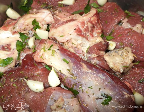 Выложите мясо, затем несколько зубчиков чеснока. 