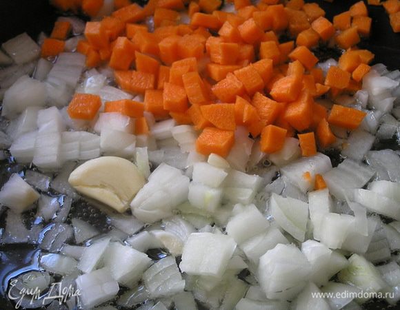 В смеси растительного и сливочного масел обжарить на медленном огне нарезанный лук, слегка придавленный зубчик чеснока и нарезанную кубиками морковь.