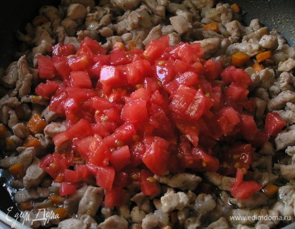 Через 2 минуты добавить очищенные от кожи и семян помидоры, нарезанные маленькими кусочками, перемешать.