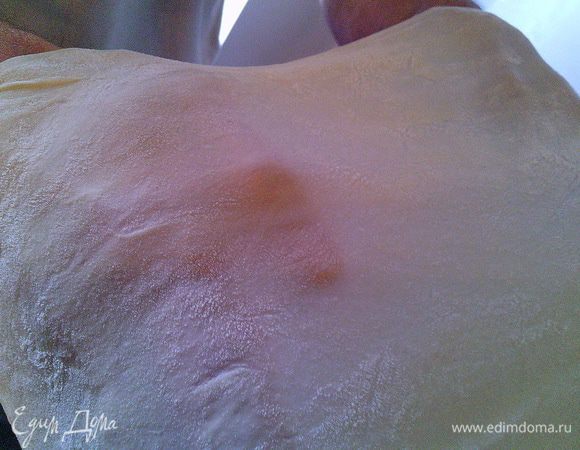 Погружаем руки в муку. Кладём тесто на тыльную сторону кистей и начинаем потихоньку как бы растягивать его, одновременно поворачивая его вокруг своей оси и двигаясь от середины к краю.