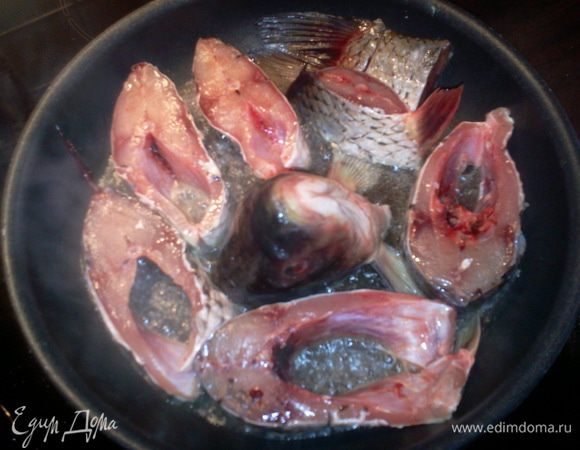 В глубокой тяжелой сковороде разогреть на сильном огне и слегка посолить растительное масло, уложить рыбу плоскостью разреза в масло, голову поставить в центре