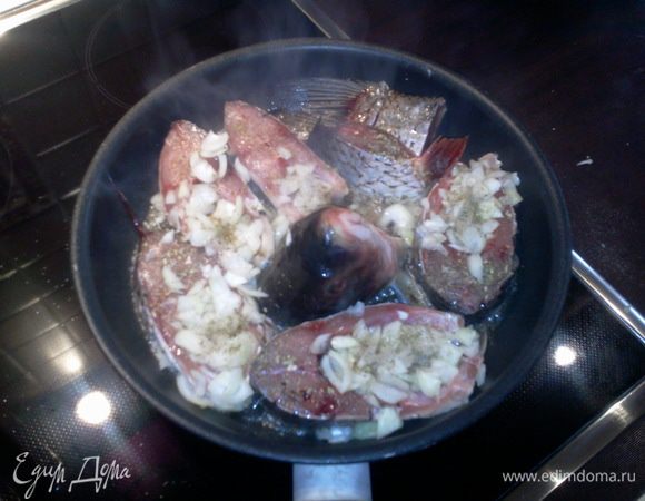 Лук посолить, поперчить, посыпать специями. Подержать рыбу с луком на сильном огне до подрумянивания лука (5 - 7 мин.) 