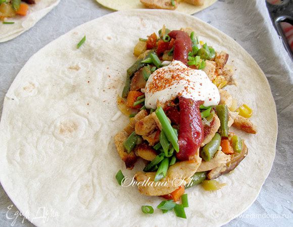 Сверху добавить сметану и острый томатный соус. Посыпать зеленым луком и тертым  сыром.
