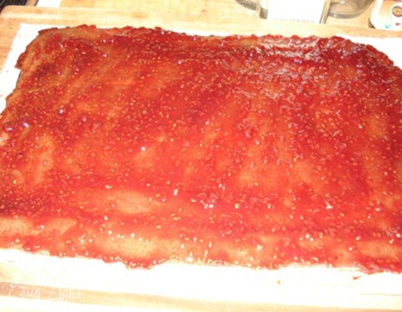 Сборка:
Бисквит снять с пергамента и перенести на новый лист пергамента.
Смазать сиропом. Затем покрыть конфитюром. Дать конфитюру впитаться.