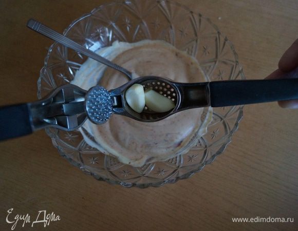 Очистить чеснок и выдавить его в сметанно-томатную смесь