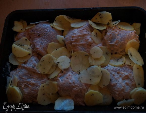 Выложить картофель к курочке и сбрызнуть оливковым маслом. Поставить в разогретую до 180 градусов духовку на 45-50 минут.