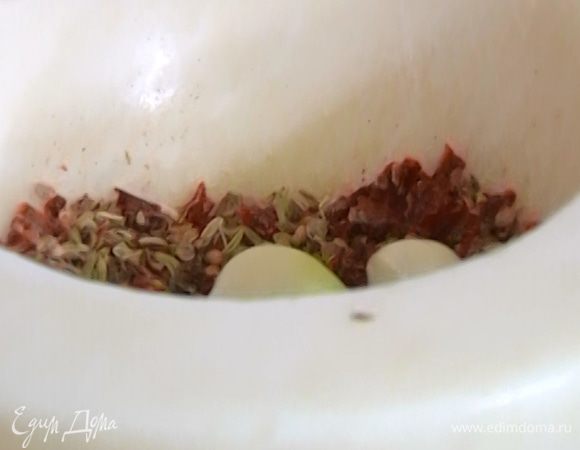 Чеснок почистить, добавить в ступку к пряностям, всыпать соль и все вместе еще немного растереть.