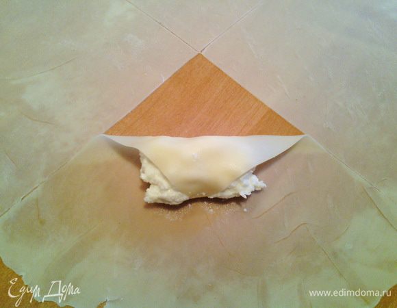 Кладём начинку ближе к уголку и начинаем сворачивать.