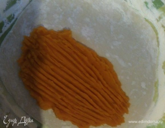 На одну половину раскатанного круга теста выложите 2–3 ложки мякоти тыквы и распределите равномерным слоем. Сформируйте полумесяц.