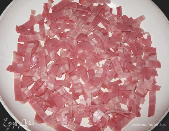 Нарезать небольшими полосками бекон, слегка обжарить его на сковороде, чтобы вытопился жир. Вынуть бекон на тарелку. 