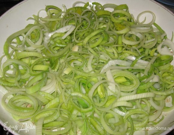 Нарезать тонкими кольцами лук порей. 
В сковороду добавьть немного растительного масла и слегка припустить в нем лук. 