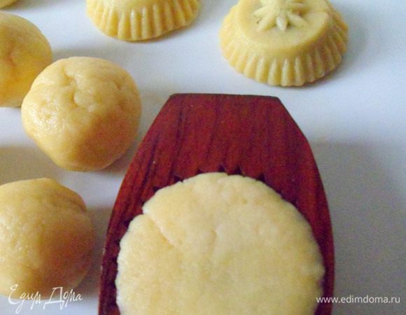 Затем положить шарик из теста с финиковой начинкой в формочку, слегка как бы придавливая. Формочка резная, вот для этого нужно придавливать, чтобы получился рисунок. Затем стукнуть формочку об стол, чтобы печенье вылетело уже фигуристое.