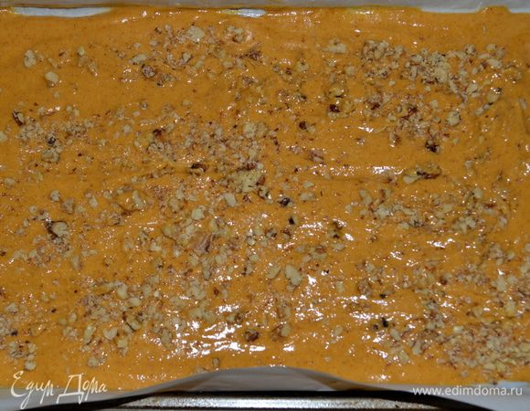 Добавить муку и перемешать вновь. Вылить тесто на приготовленный противень и распределить лопаткой. Сверху выложить орехи/по желанию/.