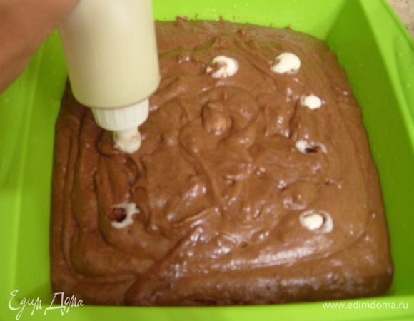 Начинку поместить в кондитерский мешок с гладкой насадкой. Отсадить начинку внутрь теста с помощью кондитерского мешка. Выпекать в разогретой до 170 °С духовке 40 минут. После выпечки и охлаждения нарезать на квадраты и посыпать какао-порошком.