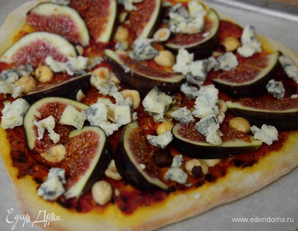 Достать пиццу (духовку не выключать), выложить на нее , нарезанный дольками инжир и сыр (предварительно разломав его на кусочки.) Отправить в духовку минут на  5 - 7. 