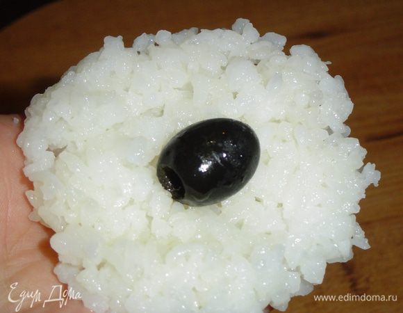 В воде разводим ложку рисового соуса, смачиваем руки, формируем из риса лепешки, в центр кладем маслины,