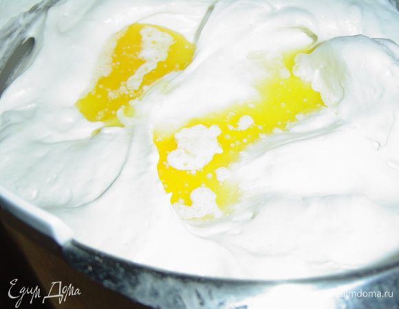 Отделяем белки от желтков. Белки взбиваем со щепоткой соли до мягких пиков, затем постепенно добавляем 150 грамм сахара и взбиваем до устойчивых пиков. Муку просеиваем с разрыхлителем, добавляем к белкам и аккуратно, лопаткой, перемешиваем, в конце добавляем растопленное сливочное масло и еще раз перемешиваем.