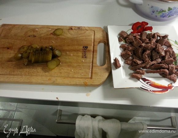 Добавляем мясо и соленый огурец. Заливаем бульоном, чтобы покрывало мясо. Перемешиваем и ставим режим "тушение".