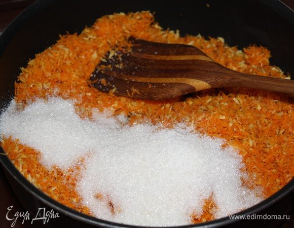 Добавьте к моркови и стружке сахар, перемешайте и обжаривайте 10 мин, постоянно помешивая.