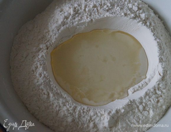 Насыпать муку горкой, сделать в ней углубление, немного посолить и налить воду, начать замешивать нежное тесто.