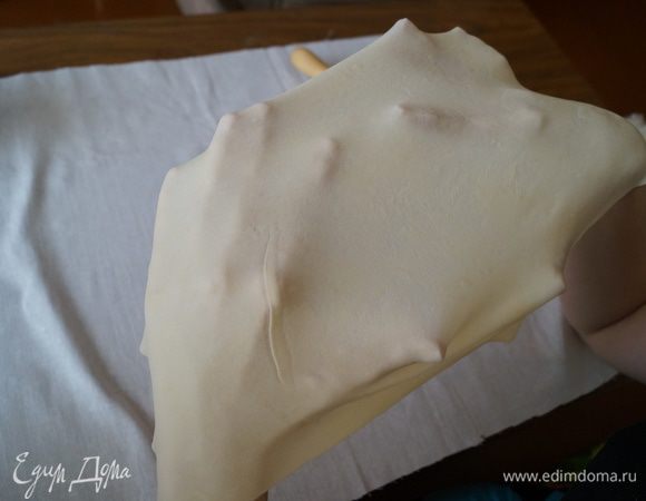 После того как тесто тонко раскатано, взять его за края и вытянуть в разные стороны. Затем взять и положить тесто на тыльную сторону рук и еще его немного потянуть. Чем тоньше получится тесто, тем лучше (оно должно просвечивать).  Готовое тесто, что бы оно не высохло, накрыть влажным полотенцем.