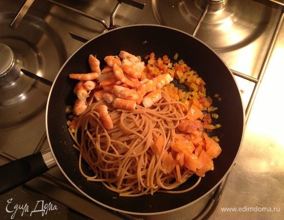 К луку и помидорам выложить макароны, креветки и нарезанной кусочками семги. Протушить все вместе пару минут.

