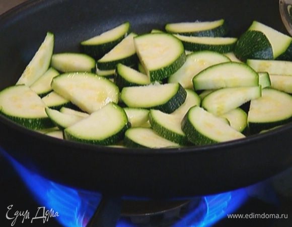 Разогреть в сковороде со съемной ручкой оливковое масло и обжарить цукини.