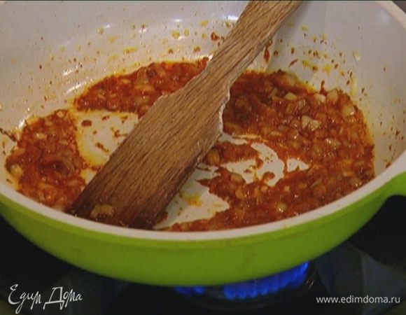 Выложить к луку нарезанную курицу, пасту карри, томатную пасту, перемешать и продолжать готовить на медленном огне.