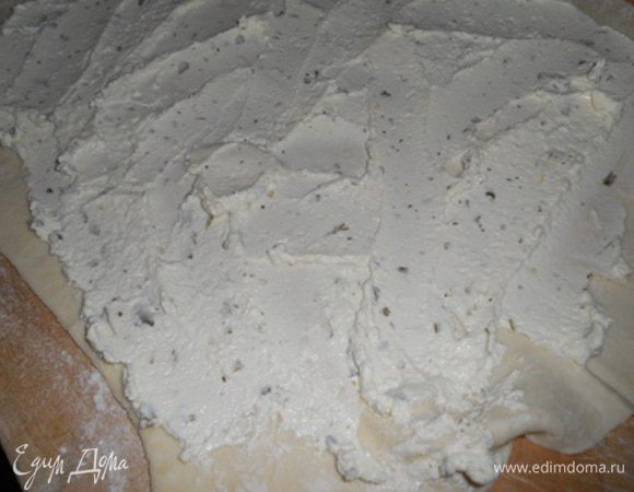 Теперь взять 2 листа теста положить край к краю и раскатать одним сплошным пластом, поверхность смазать сливочным сыром и свернуть рулетом.